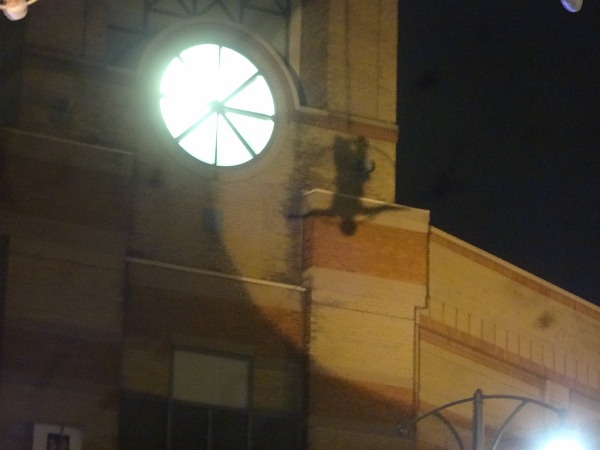 The silhouette of an acrobat is cast against the City Centre clock tower