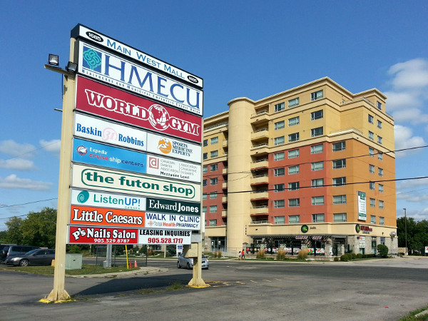Main West Mall sign with student apartment across the street