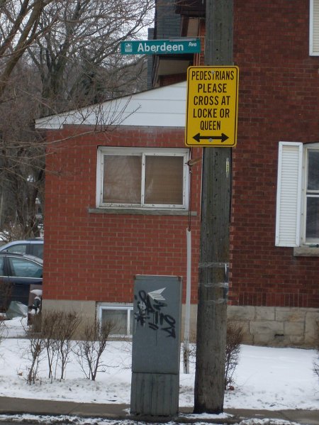 Sign at Aberdeen Ave. and Kent St: 'Pedestrians Please Cross at Locke or Queen'
