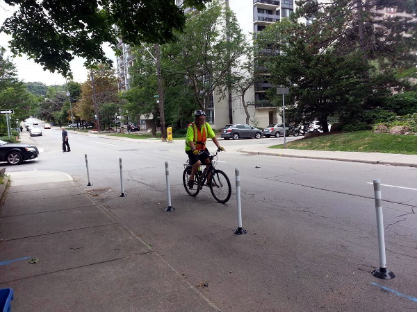 Cyclist riding in mixed traffic next to knockdown sticks