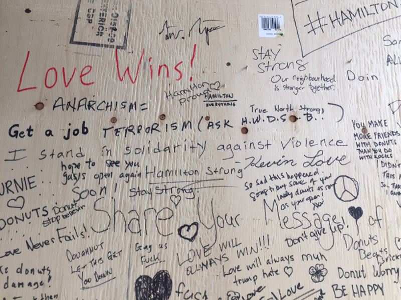 Messages of support on the plywood window covering at Donut Monster