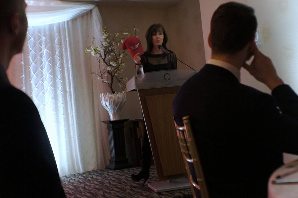 Donna Skelly holding red MAGA-styled 'Free Bird Media' hat at campus conservative event (Image Credit: Press Progress)